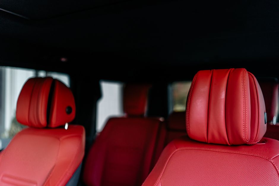 Close-up view of a luxury car interior with red leather seats and headrests.